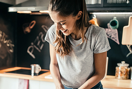 Mulher jovem sorridente cozinhando em um ambiente moderno.