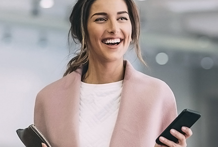 Mulher jovem elegante e sorridente segurando celular.